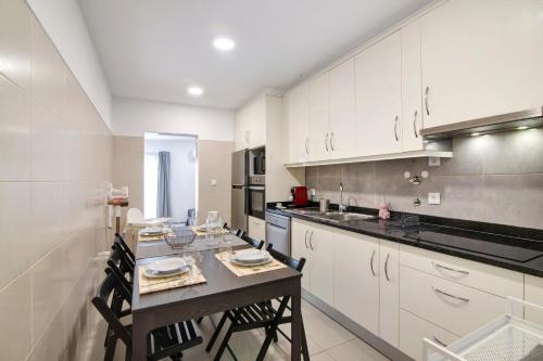 a kitchen with white cabinets and a table with chairs at Telmus Villa Rc D in Monte Gordo