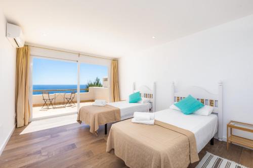 two beds in a room with a view of the ocean at Villa Domus Alba A - B in Felanitx