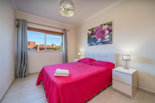 a bedroom with a pink bed and a window at Paraíso da Rocha in Portimão