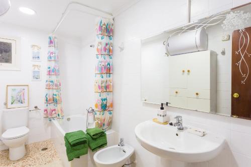 a white bathroom with a sink and a toilet at Palmera Beach House in Cullera