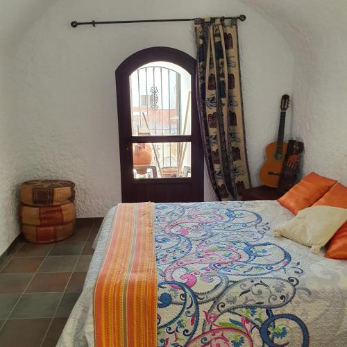 a bedroom with a bed and a window with a guitar at Cueva de Manuel in Guadix