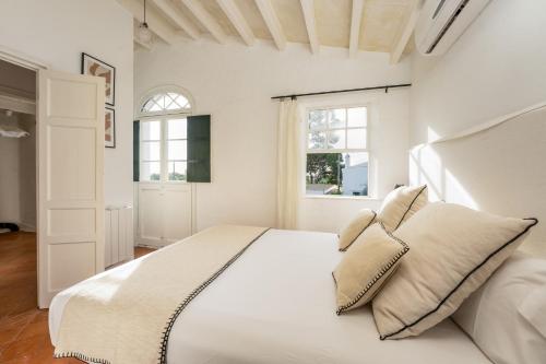 a white bedroom with a large white bed with pillows at Villa Torret 46 in Sant Lluis