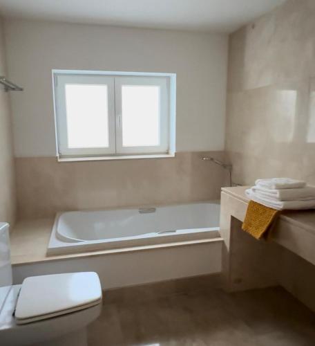 a bathroom with a tub and a toilet and a window at Apartamento Puerto Sotogrande in Sotogrande