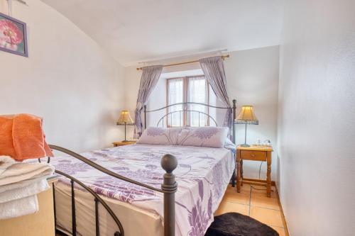 a bedroom with a bed with purple sheets and a window at Le Chai in Razac-dʼEymet