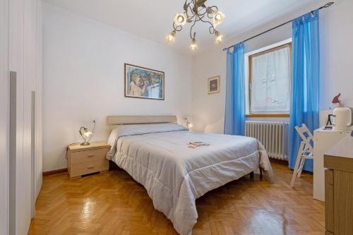 a bedroom with a bed with blue curtains and a chandelier at Camera Meridiana in Roncone