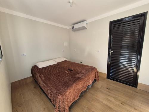a bedroom with a bed with a brown blanket at Casa com piscina em Maringá in Maringá