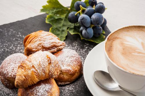 a plate of pastries and a cup of coffee and grapes at Tenuta Del Poggio Antico in Ischia