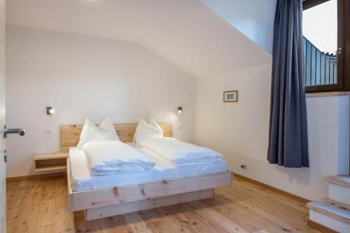 a bedroom with a bed with white sheets and pillows at Nigglhof Apartment Katarina in Redagno