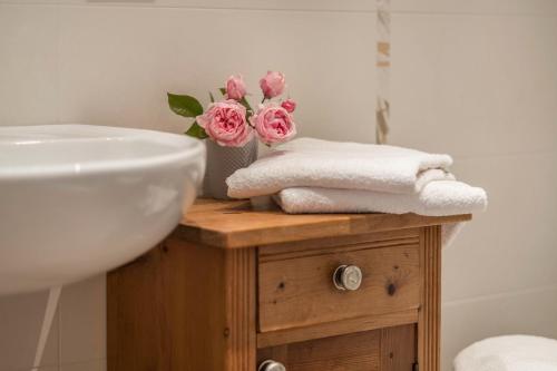 a bathroom with a sink and a vase of pink roses at Nigglhof Apartment Katarina in Redagno