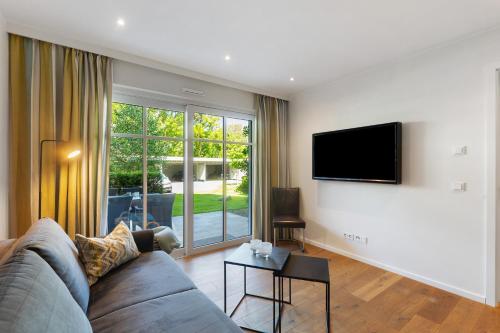 a living room with a couch and a tv on a wall at Hawerländer Apartments in Schmallenberg