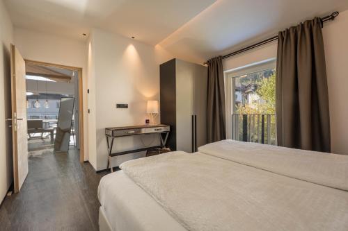 a bedroom with a bed and a desk and a window at latemar - schlosserhaus 31 in Tesimo