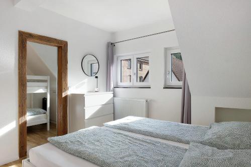 a white bedroom with two beds and a mirror at Haus Schiltach in Schramberg