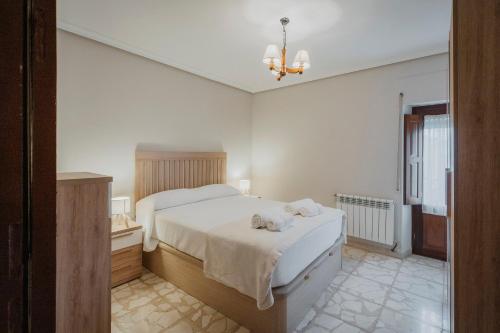 a white bedroom with a bed and a chandelier at Casa Tilde in Matapozuelos