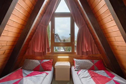 two beds in a small room with a window at Nurdach-Haus Typ 7 in Immenstaad am Bodensee