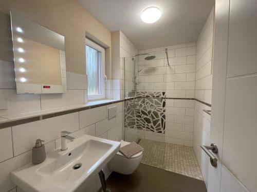a white bathroom with a sink and a toilet at Ferienhaus Pirol in Zossen