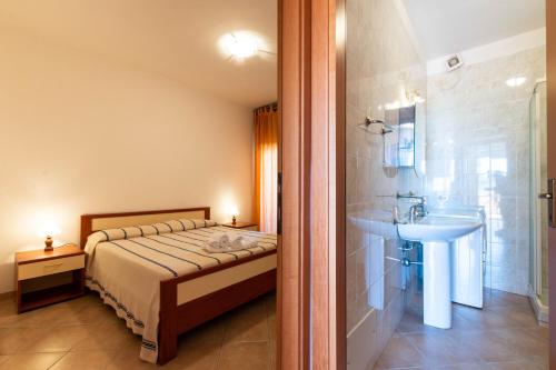 a bedroom with a bed and a bathroom with a sink at Appartamenti Cavour H in Villasimius