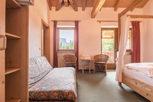 a bedroom with a bed and a table and two windows at Sabina Dolomites Zirbel in Alpe di Siusi