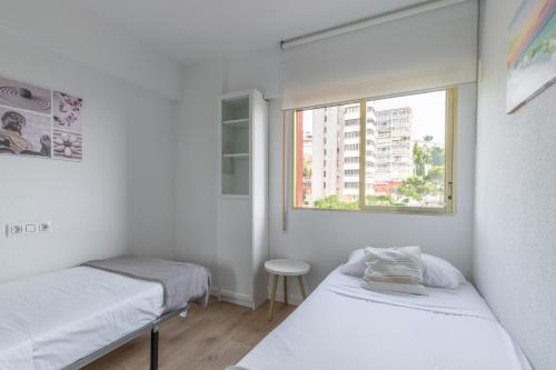two beds in a small room with a window at Don Miguel 2 in Benidorm