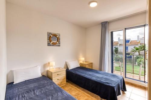 two beds in a room with a window at Oasis Premium Costa Brava in L'Estartit
