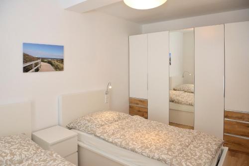a white bedroom with two beds and a mirror at Apartment Serles in Mühlbachl