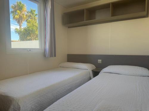 two beds in a room with a window at Coral Bungalow in Ayamonte