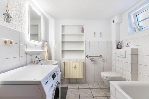 a white bathroom with a washing machine in it at Ferienwohnung zur Ostsee in Westerholz