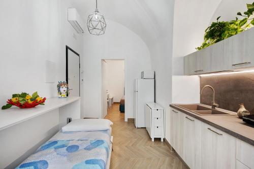 a kitchen with white cabinets and a sink and a bench at Lubrense Signature Suites in Massa Lubrense