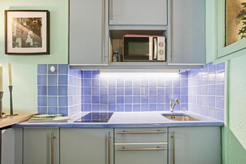 a blue tiled kitchen with a sink and a microwave at Un Petit Paradis à Gigaro in La Croix-Valmer