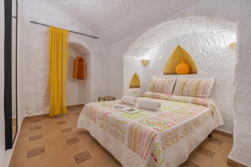a bedroom with a bed with a white wall at La Higuera in Benalúa de Guadix