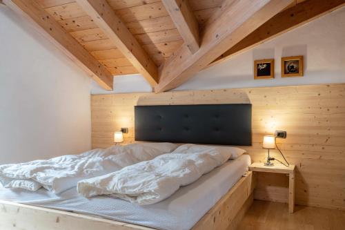 a large bed in a room with wooden ceilings at Apartment Vajolet in Campitello di Fassa