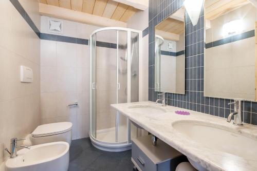 a bathroom with two sinks and a shower and a toilet at Apartment Vajolet in Campitello di Fassa