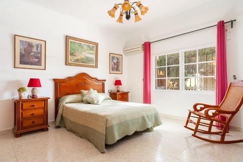 a bedroom with a bed and a chair and a window at Casa Chiqui - solo familias in Conil de la Frontera
