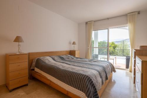 a bedroom with a bed and a large window at Casa Curumbico in Almuñécar