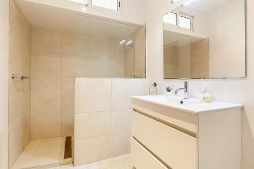 a white bathroom with a sink and a shower at Bruc Apartment Beach in Canet de Mar