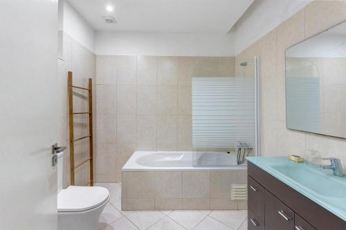 a bathroom with a tub and a toilet and a sink at T2 Furadouro 30m from the beach in Ovar