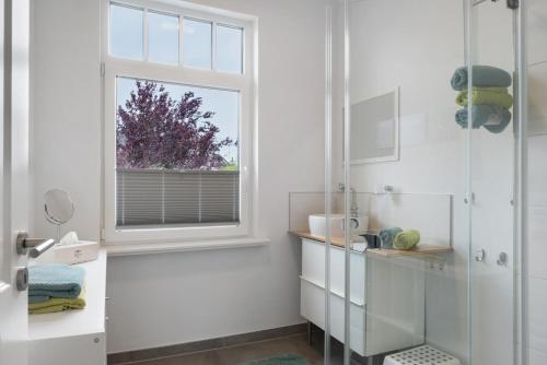 a white bathroom with a shower and a window at Ferienwohnung Alte Liebe in Cuxhaven