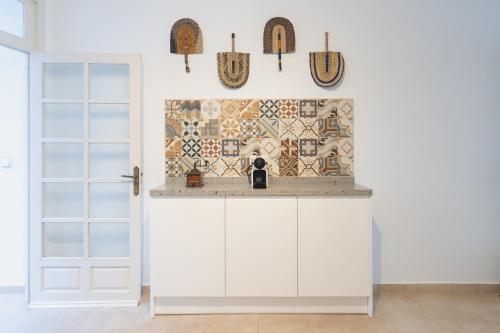 a kitchen with white cabinets and a tile wall at Casa Blanca in Estepona