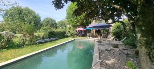 a swimming pool in a yard with an umbrella at Au fil de l'eau in Chambonas