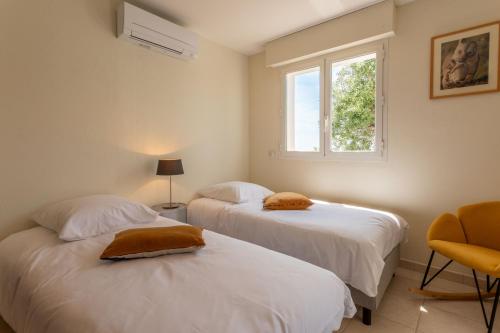 two beds in a room with a window at Le Plein Sud Terrasse vue mer Agay in Saint-Raphaël