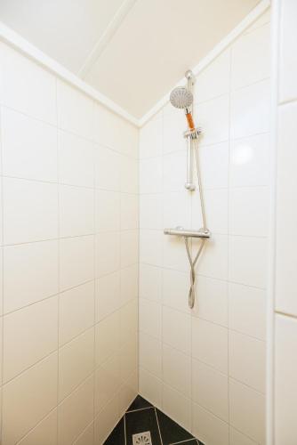 a white tiled shower with a shower head at Buitengoed het Lageveld 137 in Hoge-Hexel