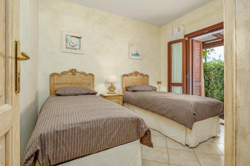 two beds in a room with a window at Mazzini Apartment - by And Service in Golfo Aranci