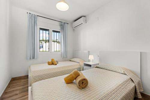 two beds in a room with white walls and windows at La Casa de la Cala del Moral in Cala del Moral
