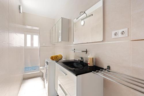 a small white kitchen with a sink and cabinets at La Casa de la Cala del Moral in Cala del Moral