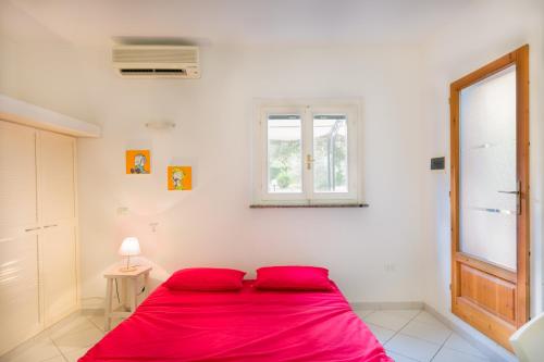 a red bed in a white room with a window at Monolocale casa Lucia in Campo nell'Elba