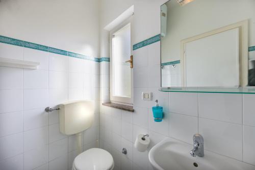 a white bathroom with a toilet and a sink at Monolocale casa Lucia in Campo nell'Elba