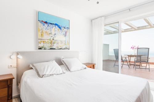 a white bedroom with a bed and a dining room at Casa Fuente del Sol in Conil de la Frontera