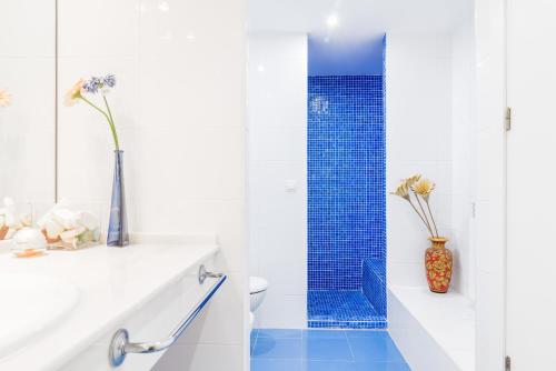 a bathroom with a toilet and a blue tile shower at Casa Fuente del Sol in Conil de la Frontera