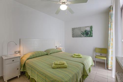 a bedroom with a bed with green and yellow sheets at Casa Médano 18 in Granadilla de Abona