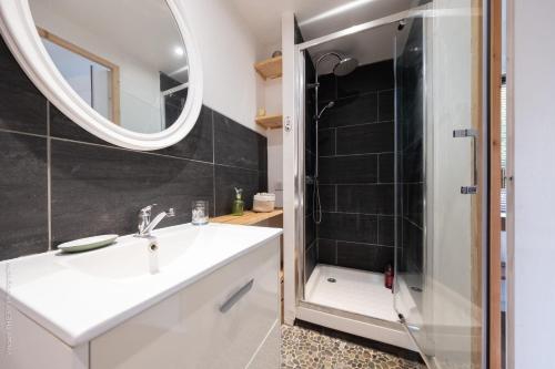 a bathroom with a sink and a shower with a mirror at Charming Gîte Le 1681 Xl in Girancourt