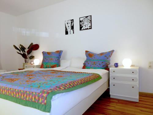 a white bedroom with a bed and a night stand at Ferienwohnung am Wald Schuttertal in Schuttertal